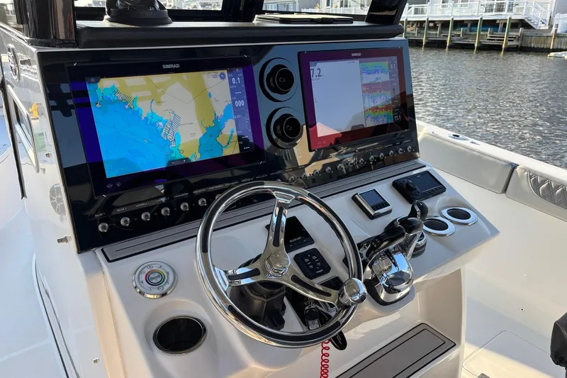 Slide: The Image of 2021 Sea Pro 320 DLX Center Console helm with dual Simrad displays and steering wheel. - 9