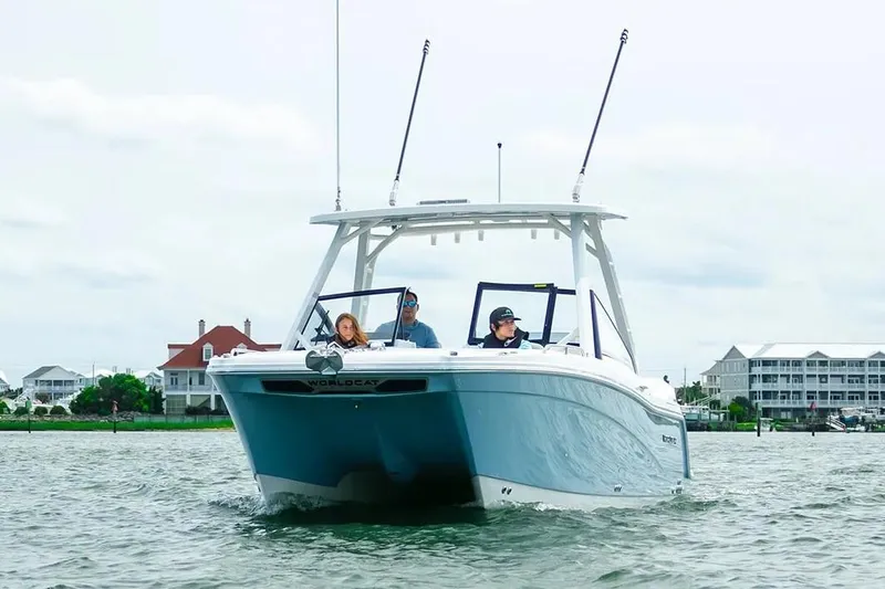 Slide: The Image of Manufacturer Provided Image: 2026 World Cat 265 DC-X boat cruising on a calm waterway near coastal homes. - 2