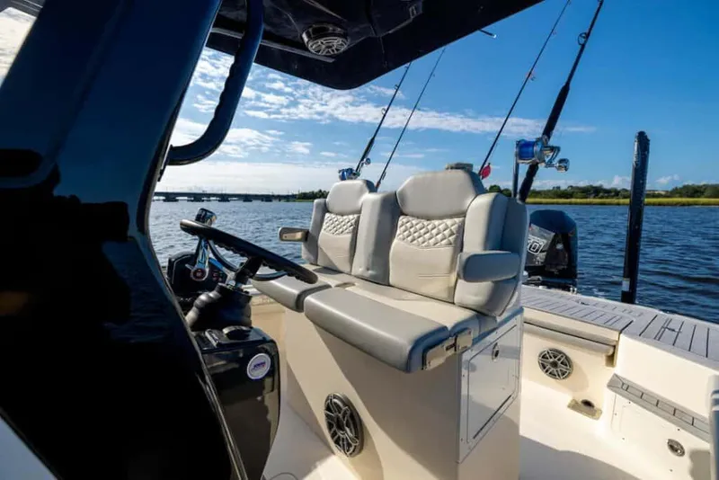 Slide: The Image of Manufacturer Provided Image: 2025 Scout 281 XSS boat interior with plush seating and fishing rods on a sunny day. - 10