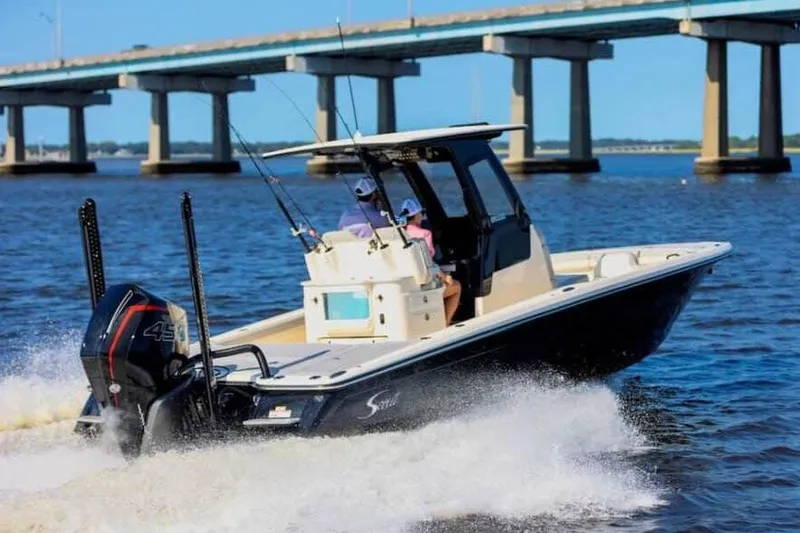 Slide: The Image of Manufacturer Provided Image: 2025 Scout 281 XSS boat cruising on water near a bridge, equipped with fishing gear. - 2