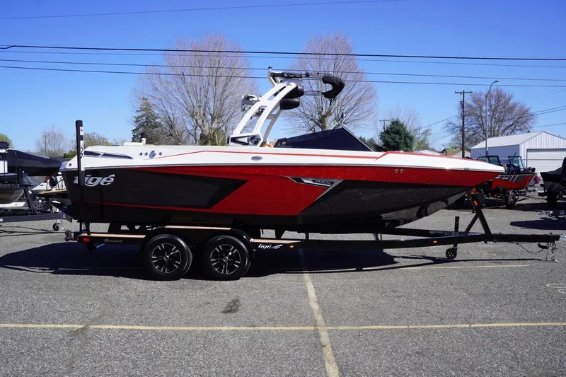 The Image of 2022 Tigé 22RZX boat in red and black on a trailer, parked outdoors. - 1