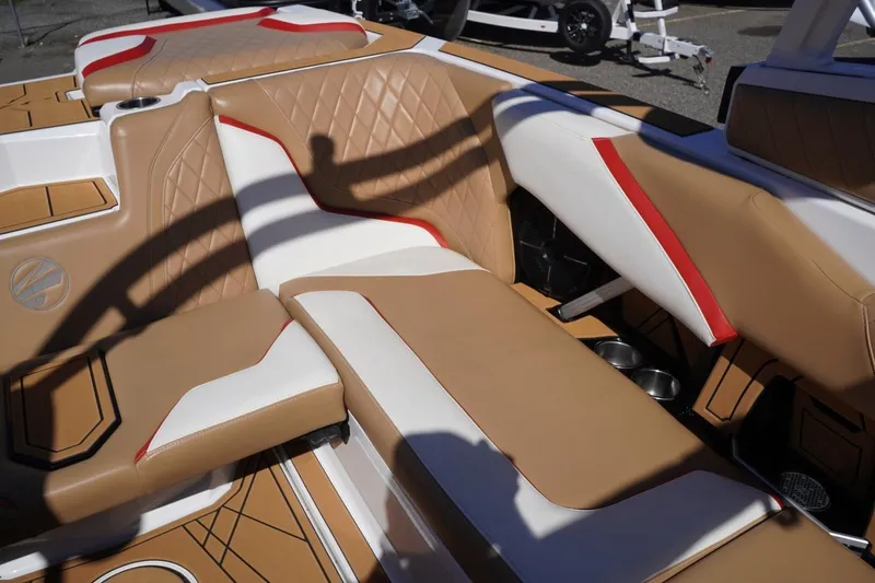 Slide: The Image of 2022 Tigé 22RZX boat interior with tan, white, and red upholstery, featuring cup holders. - 37