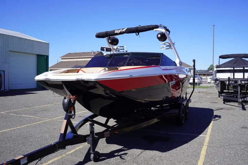 Slide: The Image of 2022 Tigé 22RZX boat on trailer, red and black design, parked outdoors. - 4