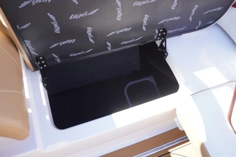 Slide: The Image of Open storage compartment in 2022 Tigé 22RZX boat, featuring branded interior lining. - 49
