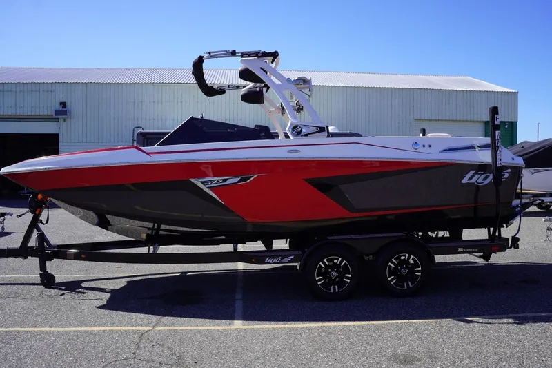 Slide: The Image of 2022 Tigé 22RZX boat in red and black on a trailer, parked outdoors. - 5