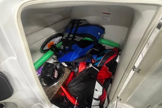 Slide: The Image of Storage compartment of 2019 Crownline Eclipse E255 SURF with life jacket and boating gear. - 39