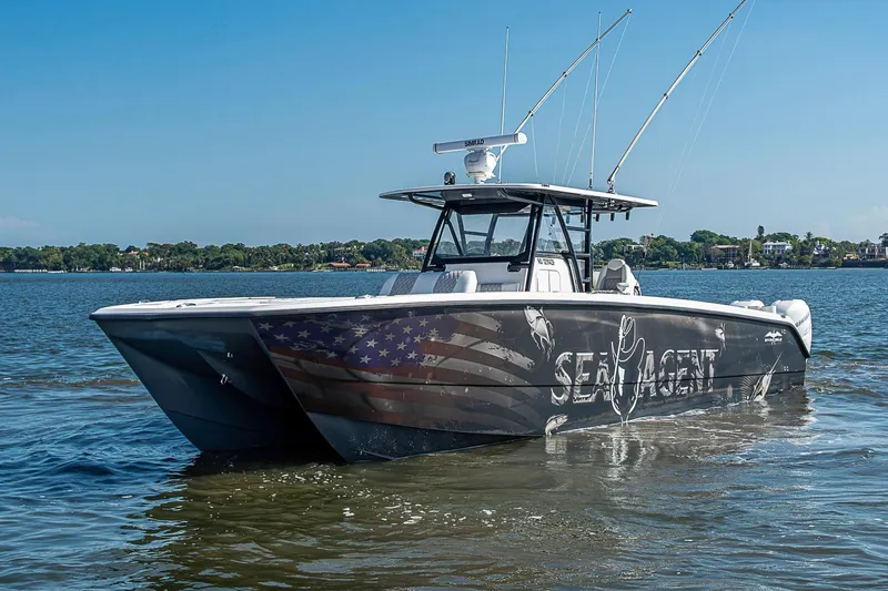 Slide: The Image of 2018 Invincible 40 Catamaran on water, featuring custom graphics and fishing rods. - 37