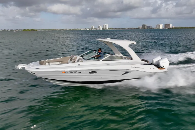 Slide: The Image of 2020 Crownline Eclipse E305 XS boat cruising on open water under cloudy skies. - 2