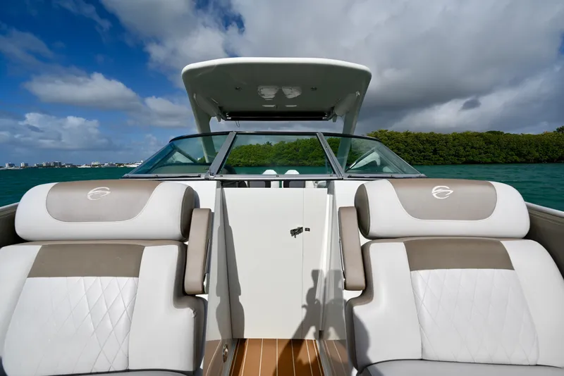 Slide: The Image of 2020 Crownline Eclipse E305 XS boat interior with plush seating, under a partly cloudy sky. - 21