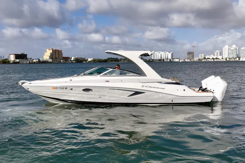Slide: The Image of 2020 Crownline Eclipse E305 XS boat cruising on a sunny day with city skyline backdrop. - 3