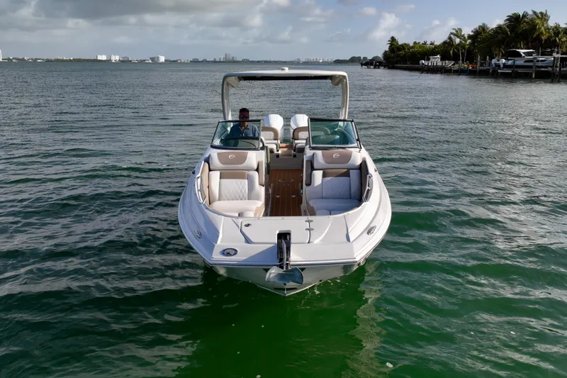 Slide: The Image of 2020 Crownline Eclipse E305 XS boat on calm water, with scenic coastal backdrop. - 5