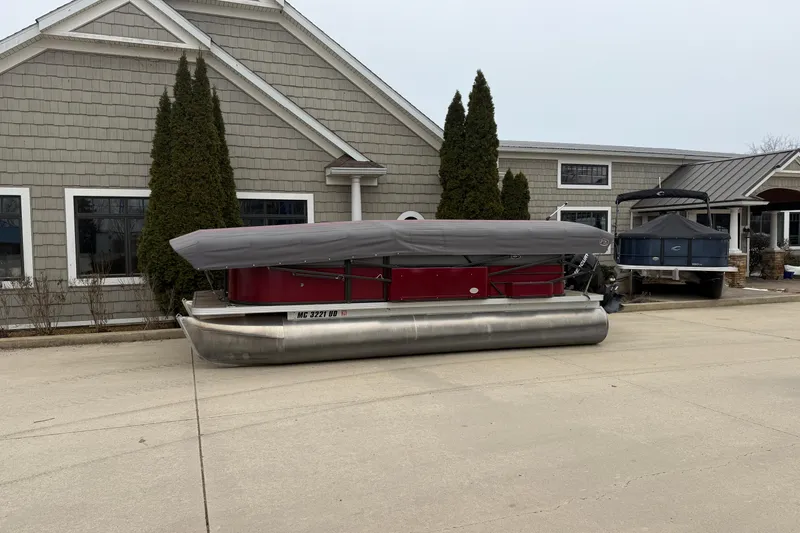 Slide: The Image of 2018 Crest I pontoon boat covered, parked outside a building. - 4
