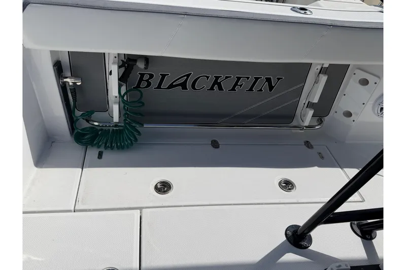 Slide: The Image of 2018 Blackfin 242 CC boat interior with cushioned seating in a marina setting. - 18