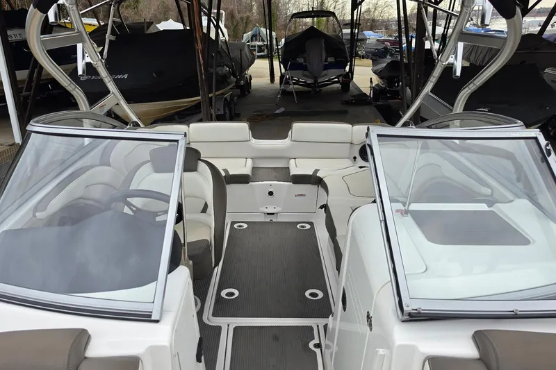 Slide: The Image of 2014 Yamaha Boats 242 Limited interior with seating and dashboard, parked in a covered area. - 10