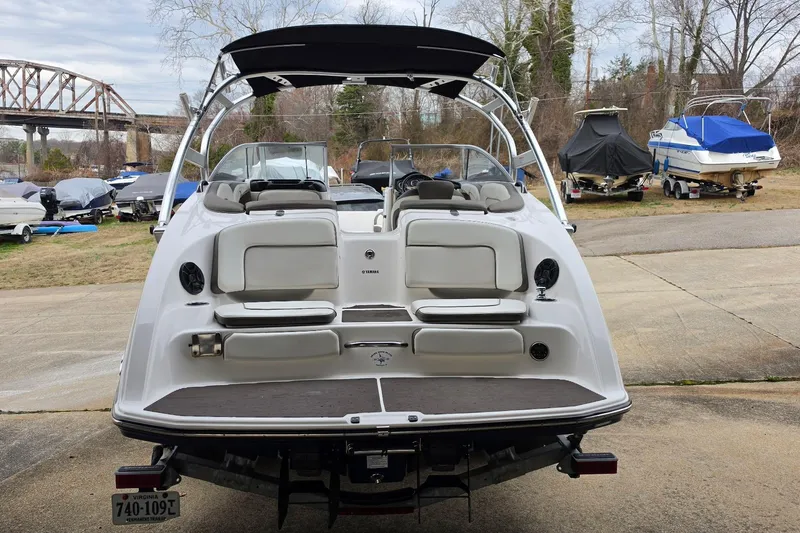 Slide: The Image of 2014 Yamaha Boats 242 Limited, rear view, parked near other boats. - 2