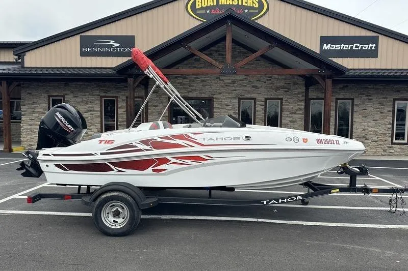 The Image of 2021 Tahoe T16 boat with red accents on trailer, parked outside dealership. - 0