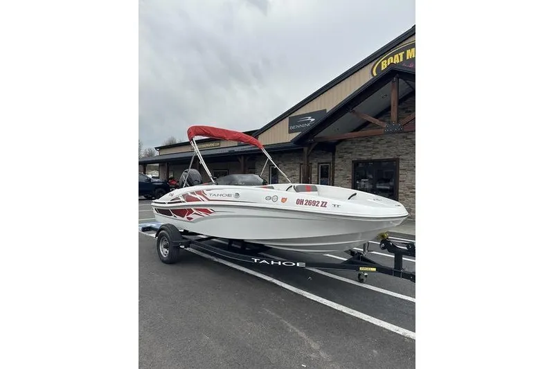 The Image of 2021 Tahoe T16 boat with red canopy on trailer, parked outside dealership. - 1