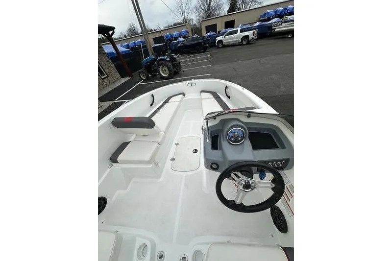 Slide: The Image of 2021 Tahoe T16 boat interior with steering wheel and seating, parked outdoors. - 9