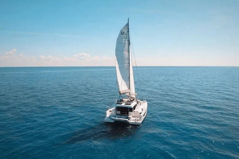 Slide: The Image of 2023 Bali CATSPACE catamaran sailing on open blue ocean under clear sky. - 1