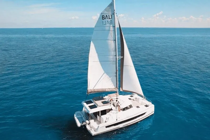 Slide: The Image of 2023 Bali CATSPACE sailing catamaran on open ocean under clear blue sky. - 2