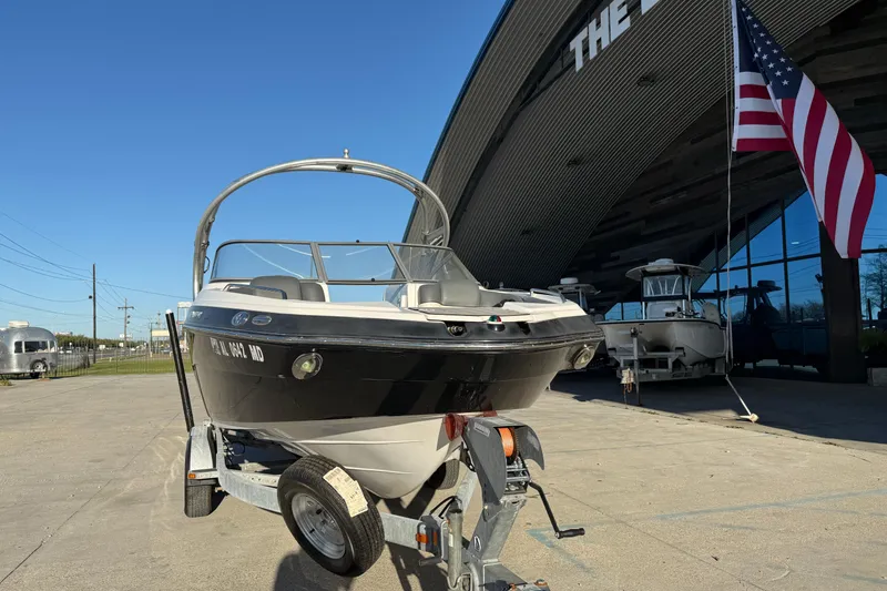 Slide: The Image of 2011 Yamaha Boats 242 Limited S on trailer outside dealership with American flag. - 3