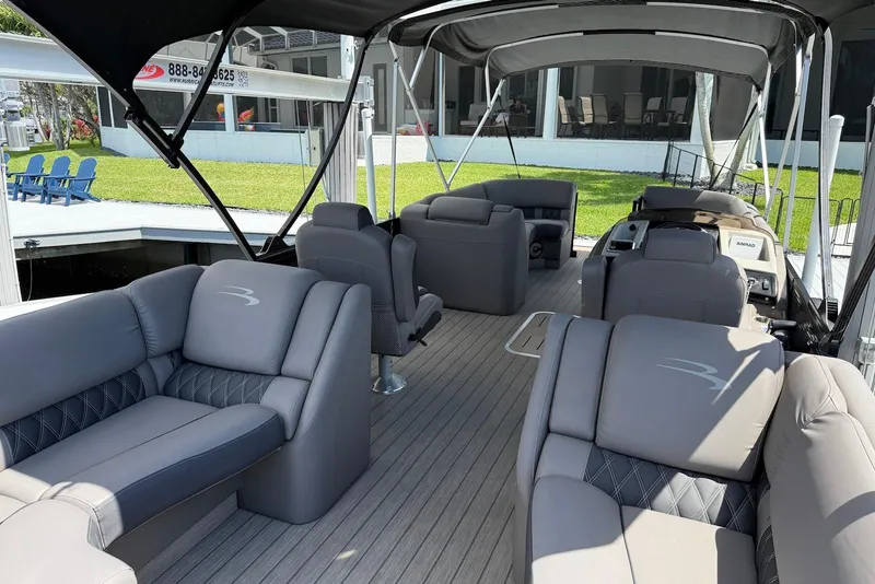 Slide: The Image of 2019 Bennington R 23 RSFB pontoon boat with luxurious seating and canopy, docked by a lawn. - 5