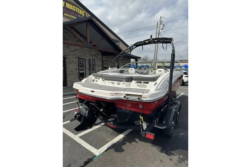 Slide: The Image of 2023 Chaparral 21 SSi boat, red and white, parked outside a marine dealership. - 10