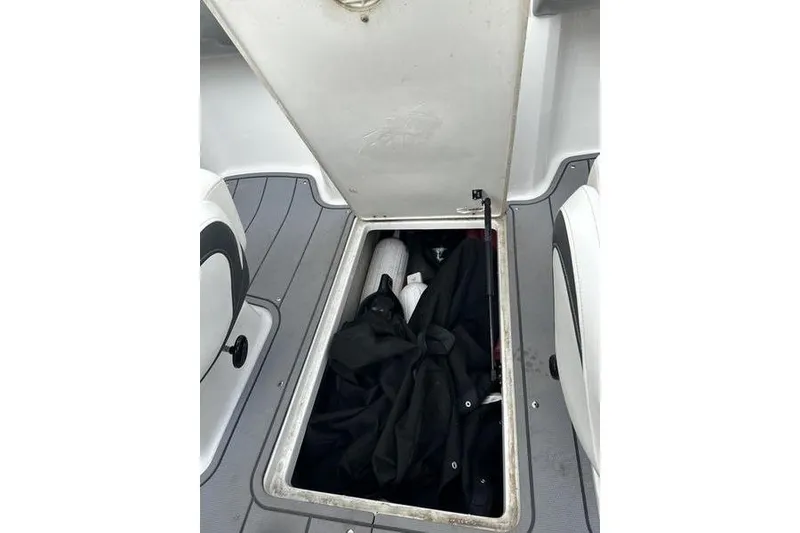 Slide: The Image of Open storage compartment in 2023 Chaparral 21 SSi boat, containing various items. - 18