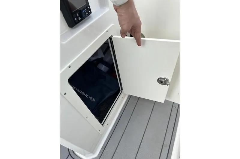 Slide: The Image of 2023 Chaparral 21 SSi boat storage compartment with open door, revealing interior space. - 21