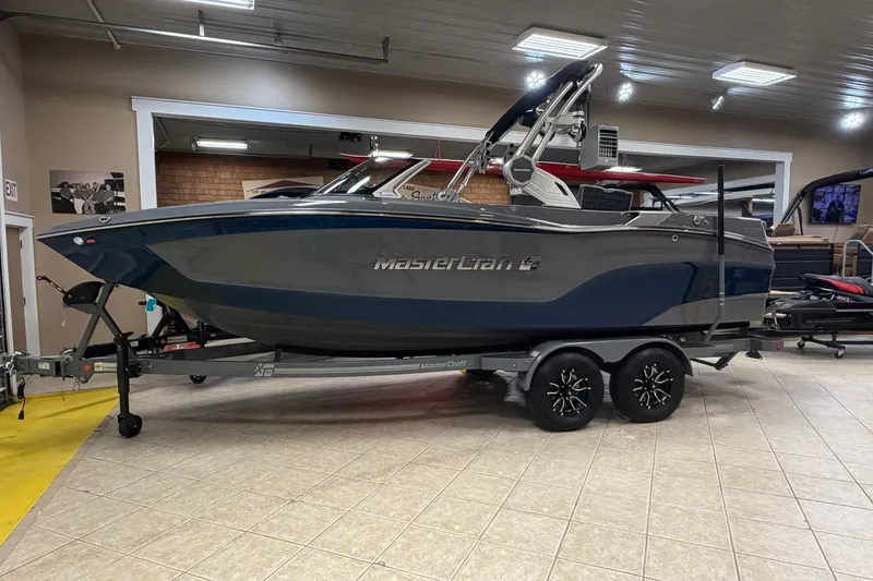The Image of 2026 MasterCraft XT22 boat on trailer in showroom setting. - 0