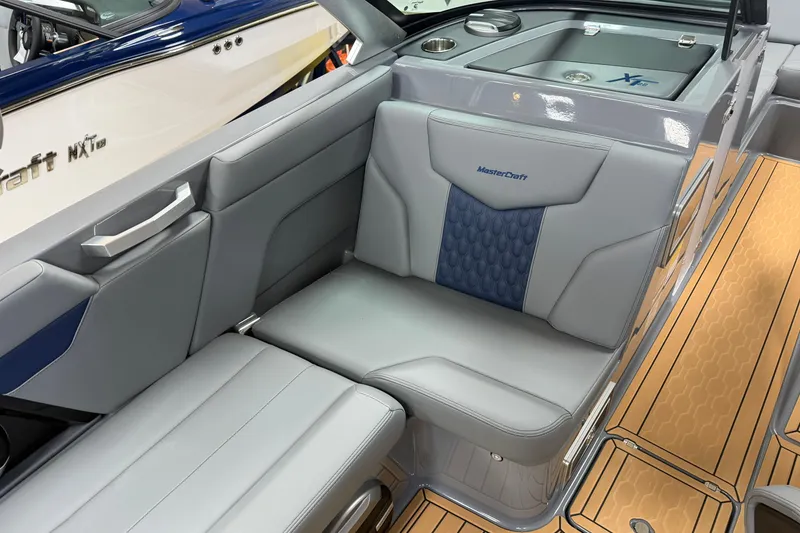 Slide: The Image of 2026 MasterCraft XT22 boat interior with gray and blue seating, wood-patterned flooring. - 8