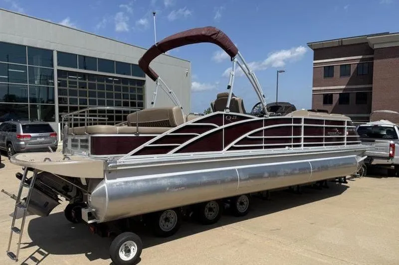 Slide: The Image of 2020 Bennington 25 QSBIO pontoon boat on trailer, parked outside a building. - 3