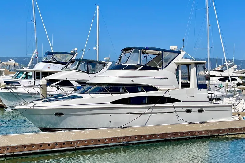 The Image of 2004 Carver 444 Cockpit Motor Yacht docked at marina under clear blue sky. - 0