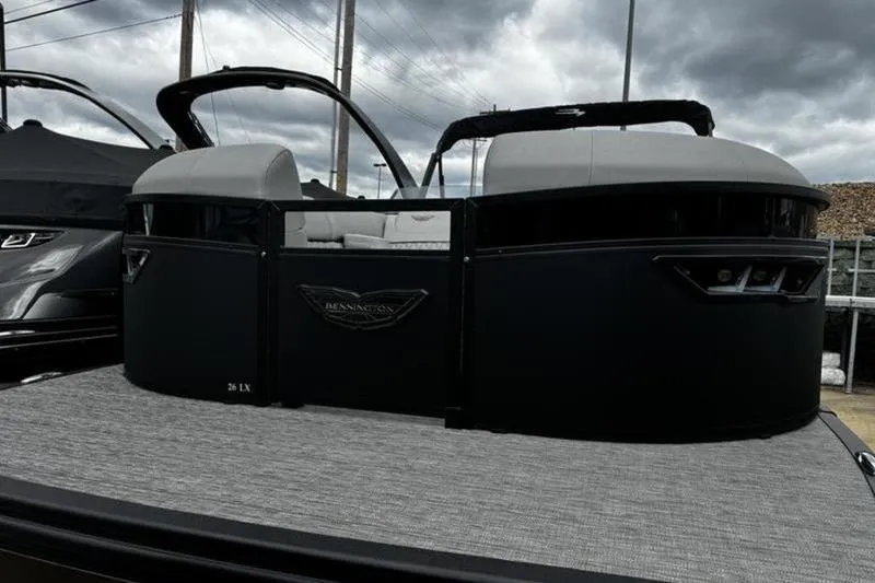 Slide: The Image of 2025 Bennington 26 LXSSB pontoon boat with sleek black design under cloudy skies. - 4