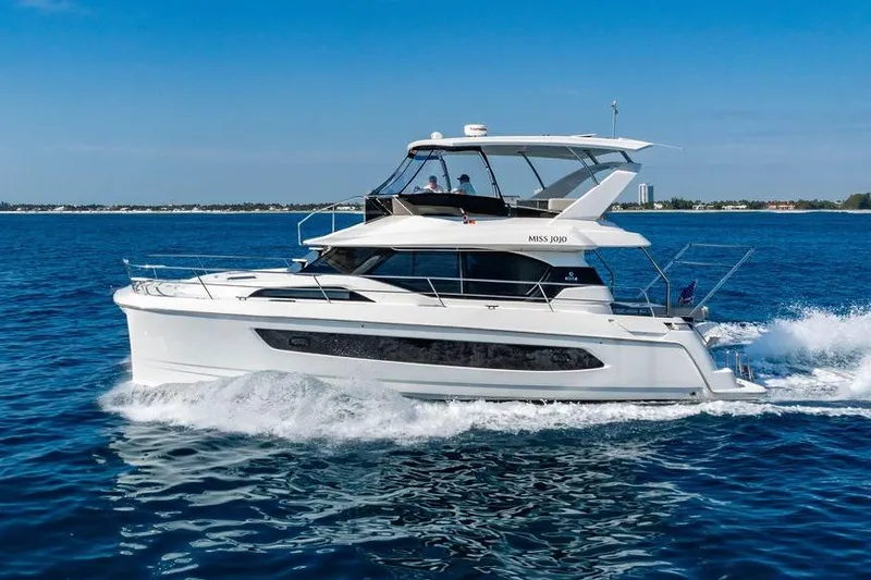 Slide: The Image of 2024 Aquila 44 Yacht cruising on open water under clear blue skies. - 14