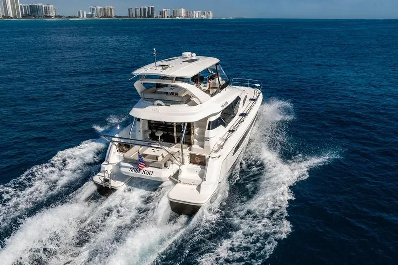 Slide: The Image of 2024 Aquila 44 Yacht cruising on open water, city skyline in background. - 27