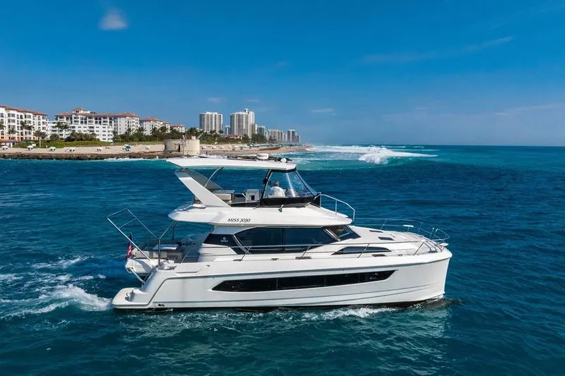 Slide: The Image of 2024 Aquila 44 Yacht cruising near coastal city skyline under clear blue skies. - 3