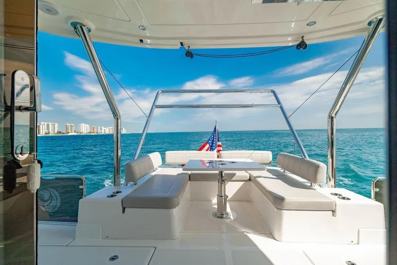 Slide: The Image of Aquila 44 Yacht 2024, luxurious deck view, ocean backdrop, city skyline, American flag. - 33