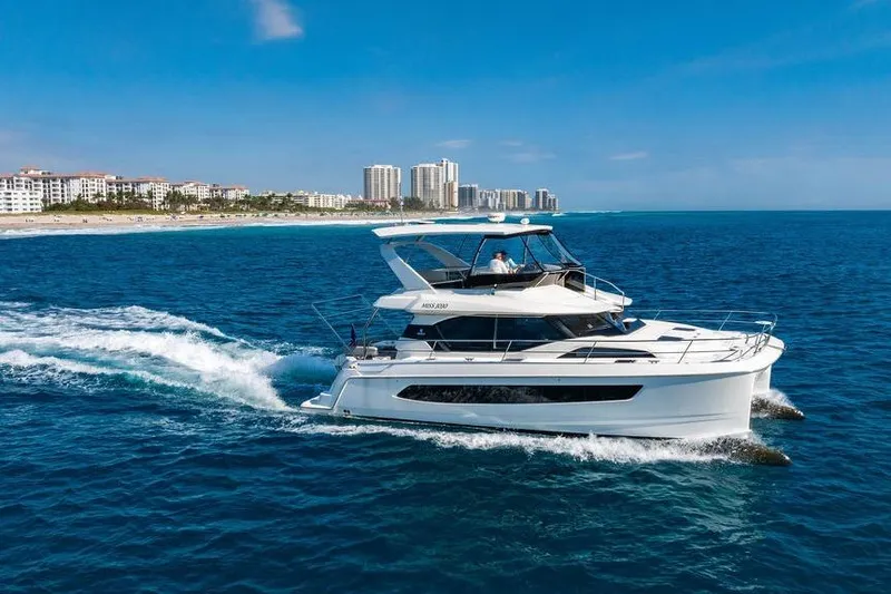 Slide: The Image of 2024 Aquila 44 Yacht cruising on blue ocean near coastal city skyline. - 4