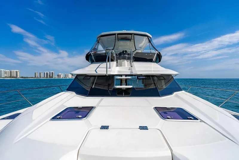 Slide: The Image of 2024 Aquila 44 Yacht cruising on blue ocean with city skyline in background. - 48