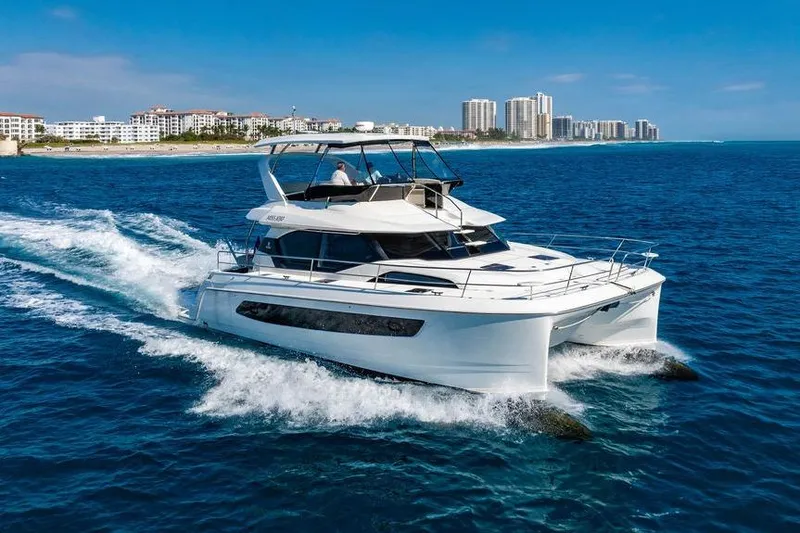 Slide: The Image of 2024 Aquila 44 Yacht cruising on blue ocean near coastal city skyline. - 5