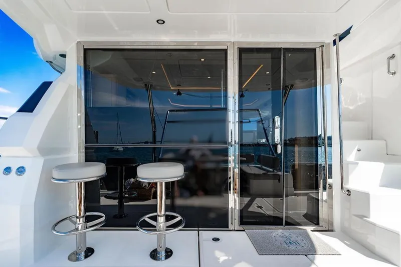 Slide: The Image of 2024 Aquila 44 Yacht with sleek glass doors and modern bar stools on deck. - 63