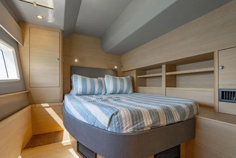 Slide: The Image of Luxurious bedroom interior of 2024 Aquila 44 Yacht with striped bedding and wooden accents. - 82