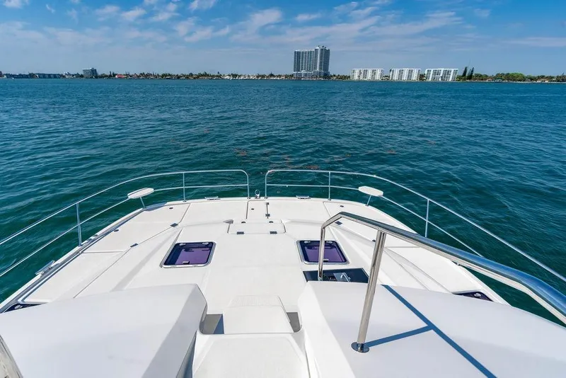 Slide: The Image of Bow view of 2024 Aquila 44 Yacht on open water, cityscape in background. - 89