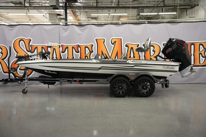 The Image of 2026 Bass Cat Puma STS boat in showroom, side view with trailer and motor. - 1