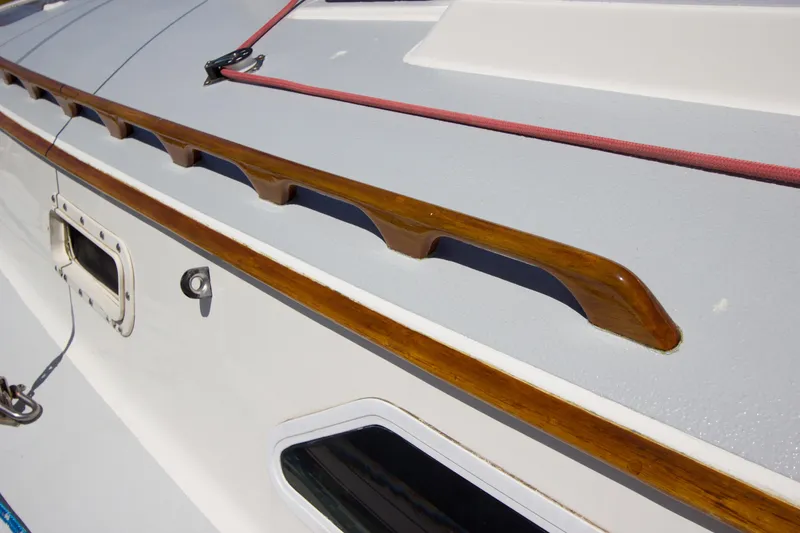 Slide: The Image of 1979 Islander Sloop deck with wooden handrail and red rope detail. - 15