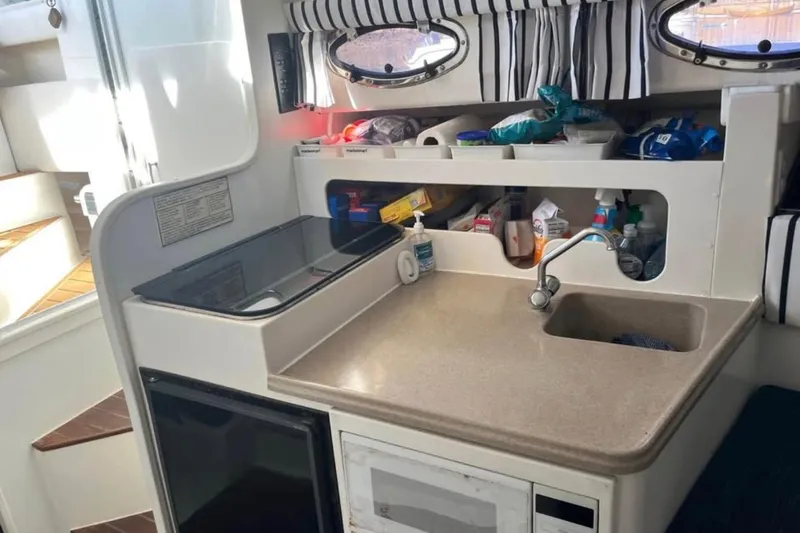 Slide: The Image of Compact kitchen area in a 2000 Stamas 310 Express boat with sink and storage. - 8