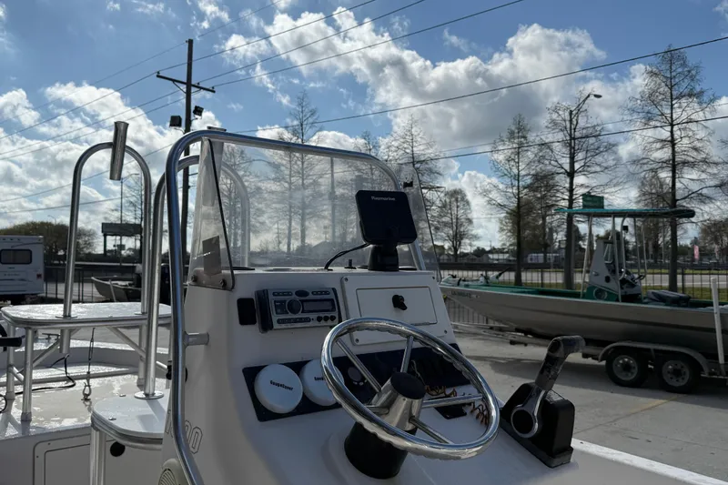 Slide: The Image of 2002 Pathfinder 1900 V boat dashboard with steering wheel and controls under a cloudy sky. - 11
