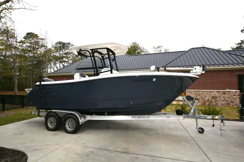 The Image of 2023 Robalo R230 Center Console boat on trailer, parked in driveway. - 1