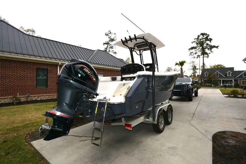 Slide: The Image of 2023 Robalo R230 Center Console boat on trailer, parked in residential driveway. - 3